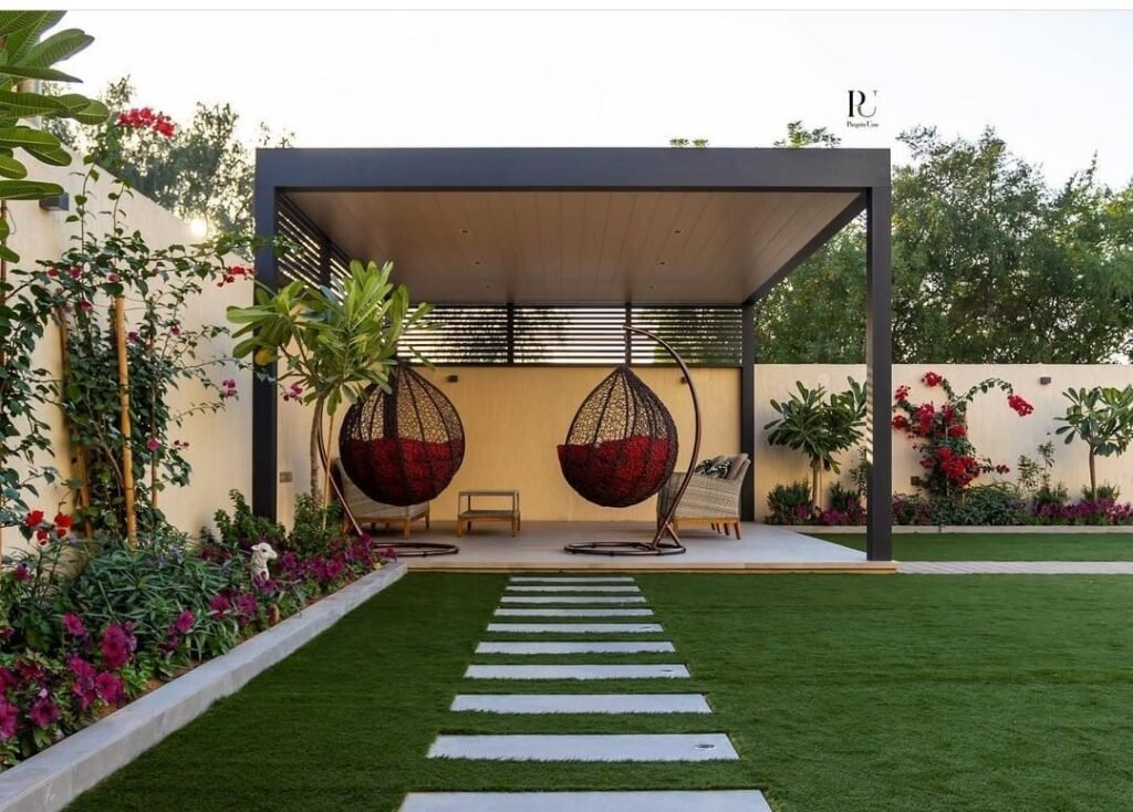 ديكور حدائق منزلية حدائق صغيرة توضح تنسيق حديقة أمامية لفيلا بالكويت، تجمع بين العشب الطبيعي وممرات حجرية ونباتات استوائية بلمسة عصرية.