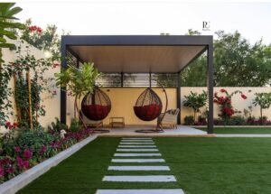 ديكور حدائق منزلية حدائق صغيرة توضح تنسيق حديقة أمامية لفيلا بالكويت، تجمع بين العشب الطبيعي وممرات حجرية ونباتات استوائية بلمسة عصرية.